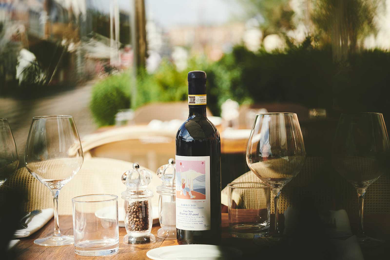 En flaske god rødvin på et opdækket bord udenfor. I solen på Il Rosmerino